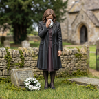 Painted lady mourner holding a handkerchief in a model churchyard