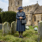 Painted lady with decorated hat and handbag in a miniature funeral scene