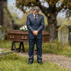 Painted mourner with clasped hands beside a model funeral setting