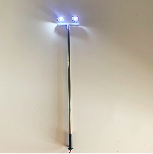 Two white LED twin-light floodlights mounted on a metal rod, intended for use with model trains.